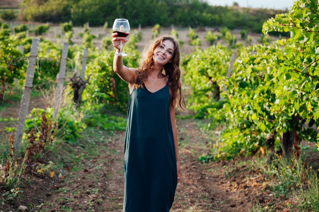 A woman exploring Indiana wineries while holding a glass of wine in a vineyard.